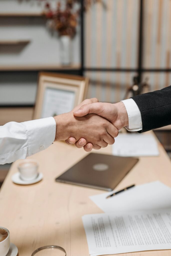 Close-up of two people shaking hands in an office, symbolizing agreement and partnership.